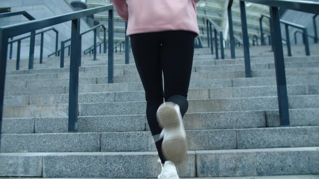 Closeup female legs running up stairs outdoor. Fitness girl climbing upstairs.
