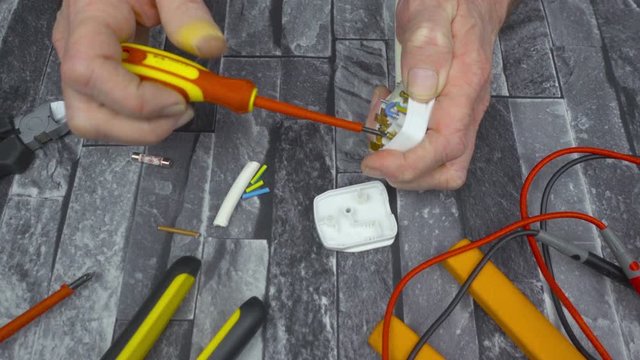 Electrical engineer using a screwdriver and  fitting a 3 pin UK plug to a white appliance cable