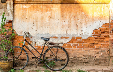 Old bike leaning against red brick wall.