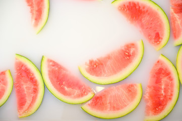 Turbid soapy water in bath with slices of watermelon. top view in full frame. The largest berry. spa with milk in the bath for rejuvenation.Ripe fruit.