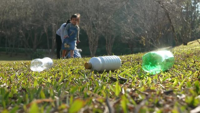 Asian family help to clean the garden by collect plastic water bottles from people who refuse to throw in the trash into plastic bags for recycling. Save environmental and reduce waste concept.