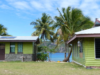 view of the sea and coconut trees betwheen two houses