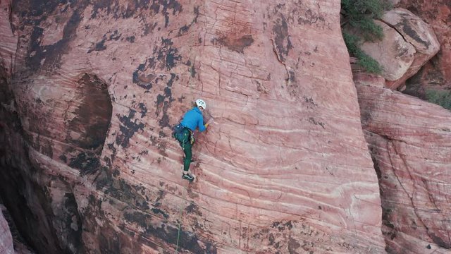 Adventurous, athletic female rock climber climbs the arete of a sandstone cliff