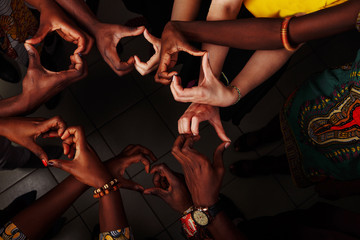 Hands in the form of heart of happy group of multinational African, latin american and european...