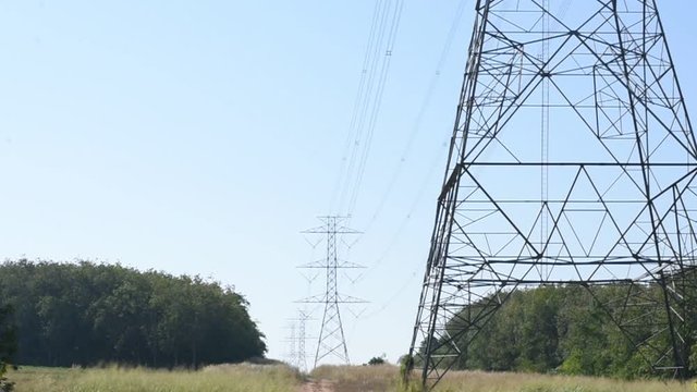 Row of electricity pole on green nature road in Thailand, Transmission line of electricity to rural, High voltage electricity pole on bright sky clouds background, electricity transmission pylon