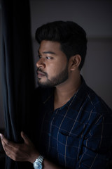Fototapeta premium an young tall, dark and handsome Indian Bengali man in a blue shirt standing in white studio background. Indian lifestyle and fashion.
