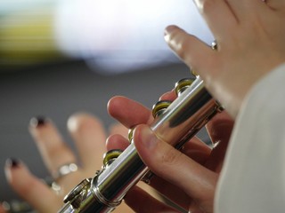 Obraz premium Hands playing notes on a flute, close up