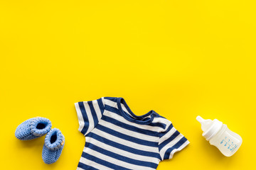 Baby background - blue color. Clothes and accessories for newborn boy on yellow table top-down frame copy space