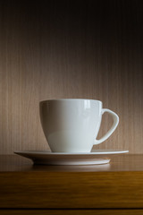 A white coffee mug on a wooden table in the morning in a wooden room