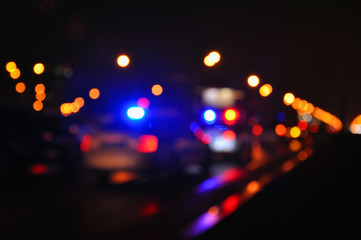 Blue light flasher atop of a police car. City lights on the background.
