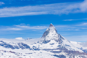 Fototapeta na wymiar Scenic view on snowy Matterhorn peak in sunny day with some clouds, Switzerland.