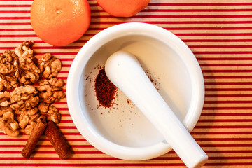 Stockholm, Sweden A mortar and pestle used to grind saffran in hot water surrounded by walnuts, cinnamon sticks and mandarins.