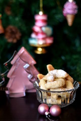 Healthy white keto almond and coconut flour cookies, sprinkled with fine grounded coconut under the Christmas tree with pink decorations. Vertical, selective focus.
