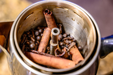 Hot liquid metal percolator with lid off showing cinnamon sticks, allspice, and cloves 