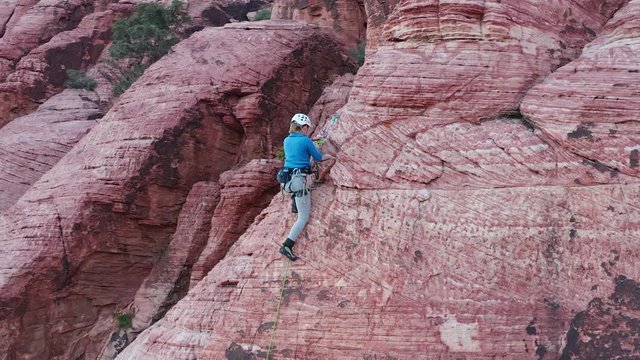 Aerial orbit shot of female rock climber securing herself safely into the anchor