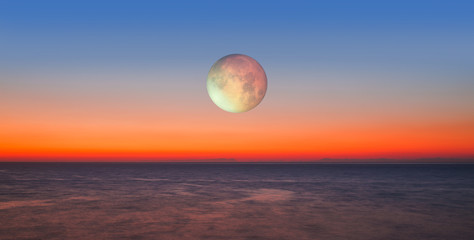 Lunar eclipse over the sea at sunset "Elements of this image furnished by NASA"