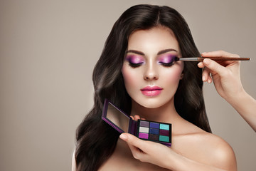 Makeup artist applies eye shadow. Beautiful woman face. Perfect makeup. Make-up detail. Beauty girl...