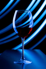 Glass of wine and lines of light. Glass with red wine on a background of abstract lines of light.
