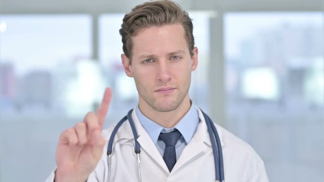 Portrait of Young Male Doctor saying No with Finger Sign
