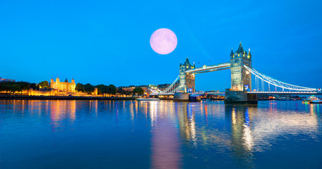 Panorama of the Tower Bridge and Tower of London on Thames river at twilight blue hour with full moon - London, United Kingdom "Elements of this image furnished by NASA"