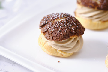 choux cream or cream puff or French profiteroles with fresh cream set on cafe table.