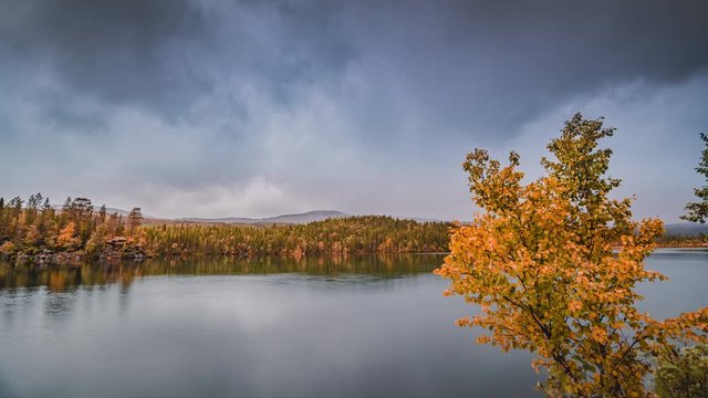 Autumn landscape on the Bleikvatnet lake, near the Bleikvasslia. Gray clouds rushing above the lake and yellowing forest. A hyperlapse video.