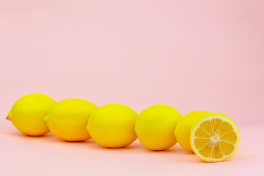 Diagonally laid lemons on a light pink background with place for text