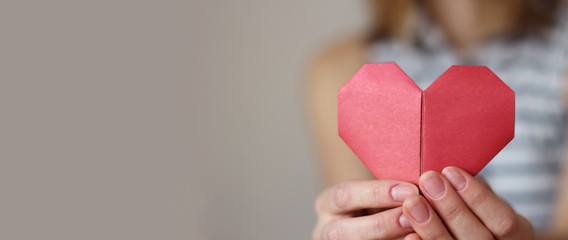 caucasian woman holding paper folded origami red heart. Insurance, charity donation concept. text...
