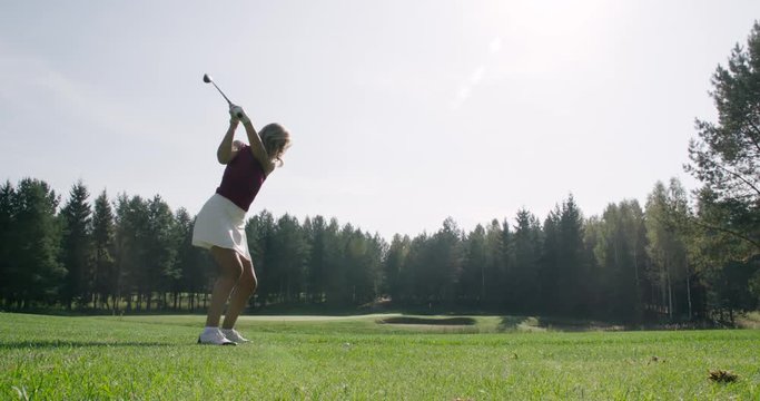 Green park, summer day, woman playing Golf, hits the ball, view of golf course in forest area, green lawn, 4k slow motion.