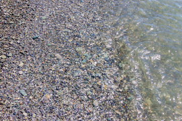 pebble coastline. Seashore  with transparent water and small stones
