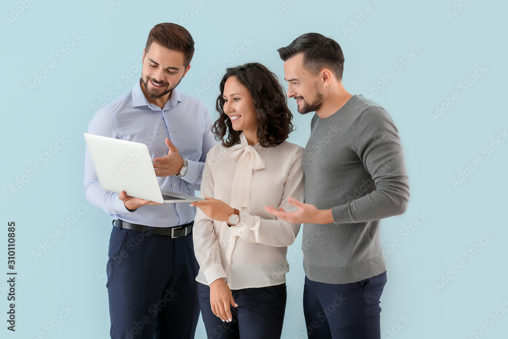 Wall mural Portrait of young business people with laptop on color background