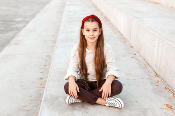 Cute fashionable girl sitting on stairs outdoors