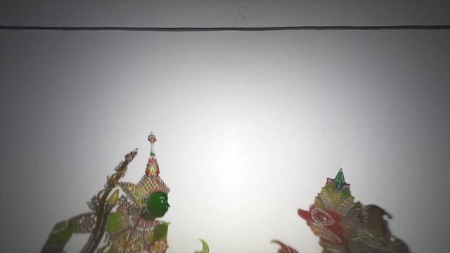 A white screen with shadow puppet play of the popular Ramayana folklore.