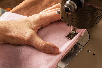 A woman sews fabric on an old sewing machine.