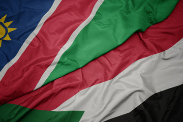 waving colorful flag of sudan and national flag of namibia.