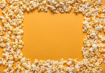 Frame made of tasty popcorn on color background