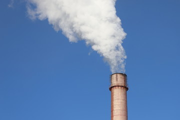 Factory chimney smoking with dense white smoke on blue sky background. Industrial pollution of air, electric plant emission,  environment ecology problem.