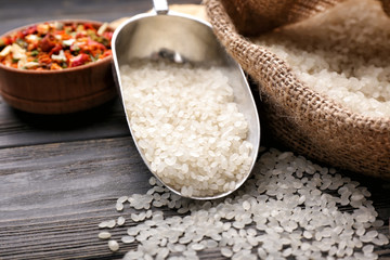 Scoop with raw rice on wooden table