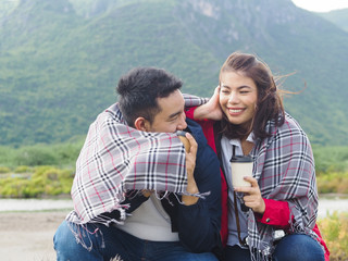 Happy Asian couple camping and drinking coffee with nature background, lifestyle concept.
