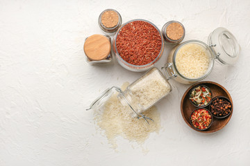 Fototapeta na wymiar Jars with different raw rice, dry vegetables and spices on white background