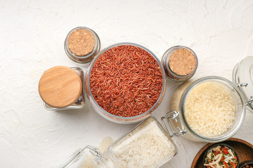 Jars with different raw rice on white background
