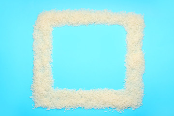 Frame made of raw rice on color background