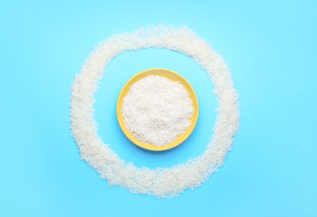 Plate with raw rice on color background