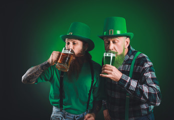 Bearded men with glasses of beer on dark background. St. Patrick's Day celebration