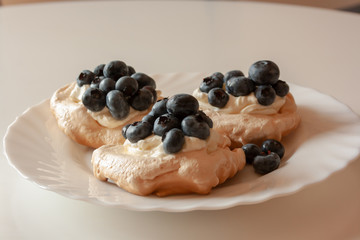 Pavlov cakes with cream and fresh blueberries on a white plate