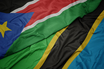waving colorful flag of tanzania and national flag of south sudan.