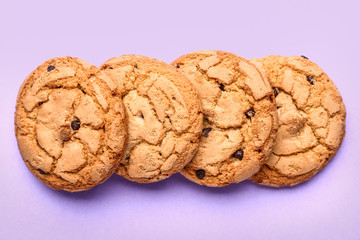 Tasty cookies with chocolate chips on color background