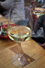 Wine glass with white wine on a table in a restaurant.