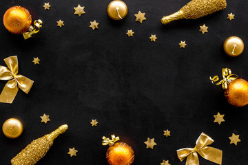 New Year mockup in gold color. Champagne bottle, present box, decoration, balls on black background top-down frame copy space