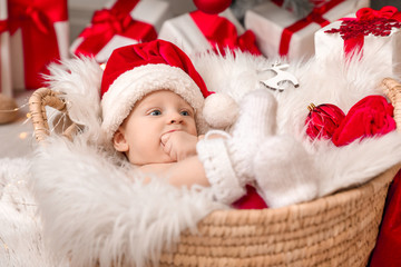 Fototapeta premium Cute little baby with Santa Claus hat lying in basket at home